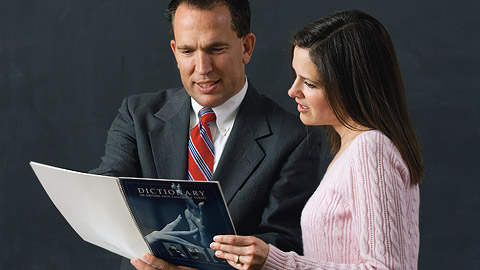 ein Mann und eine Frau betrachten ein Wörterbuch für Gebärdensprache