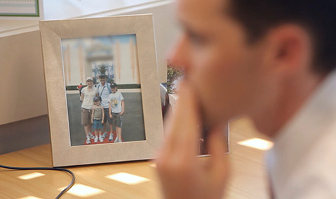 Homme de profil avec derrière lui une photo de sa famille