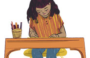 A girl colors at her desk