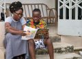 Mother and son in Ghana read the Liahona.