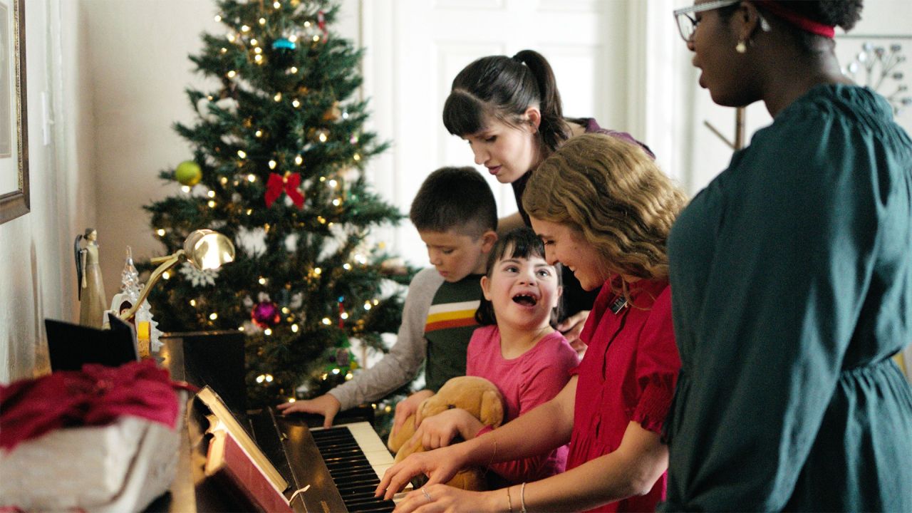Sister missionaries play the piano with a family