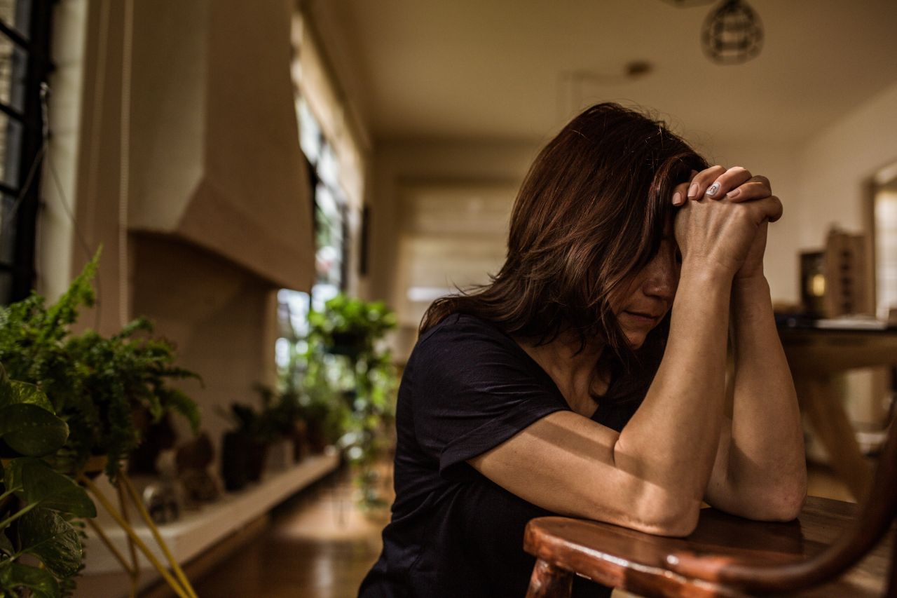 A woman prays at her kitchen table