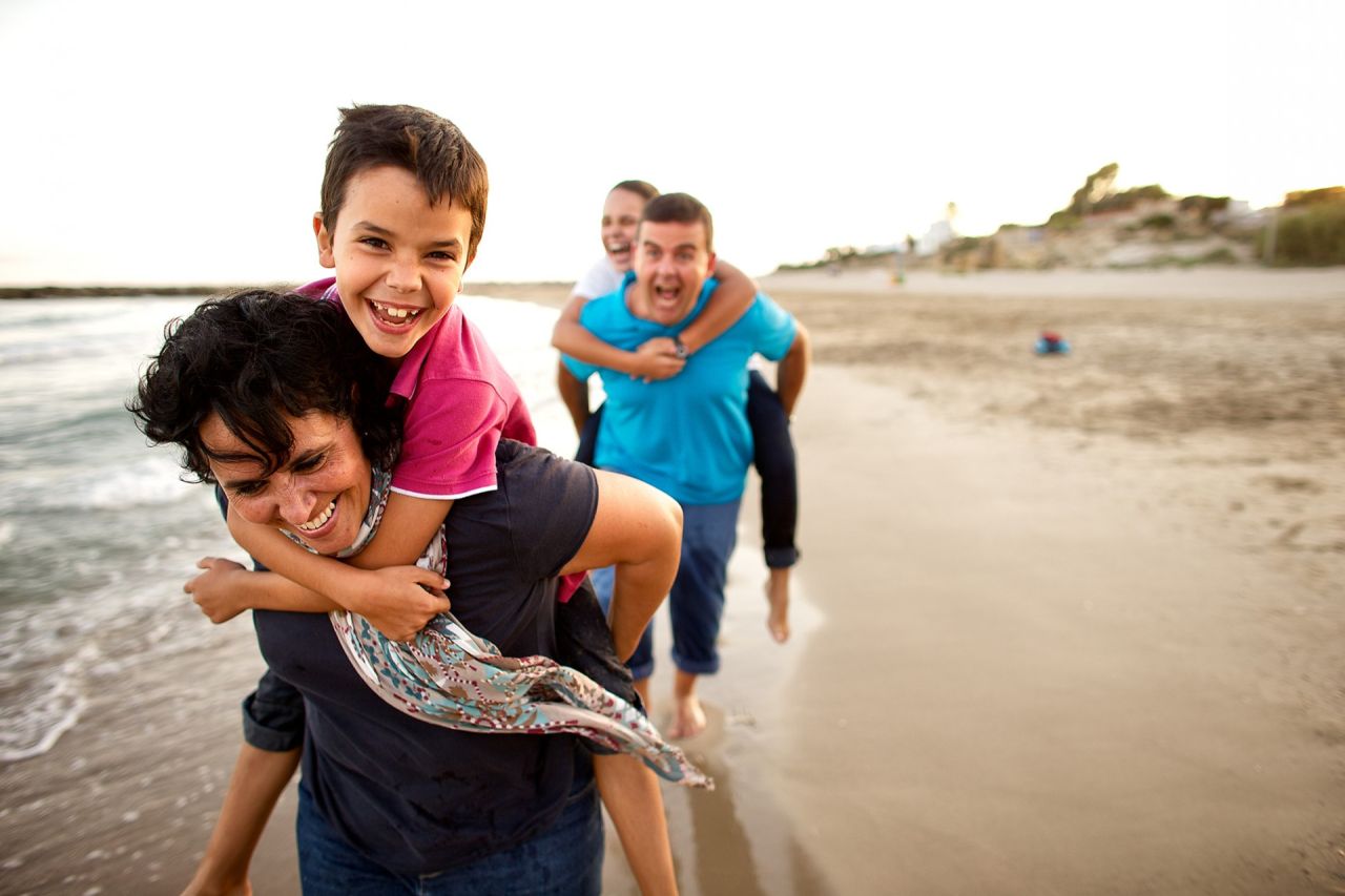 A family runs around playing on a beach enjoying each others company
