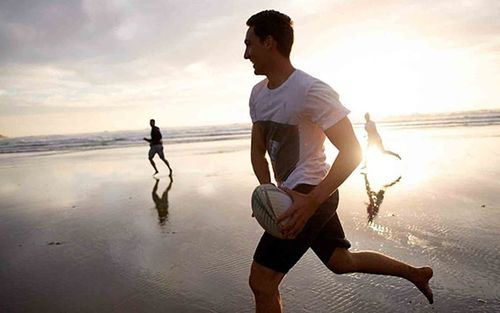 youth playing rugby on a beach