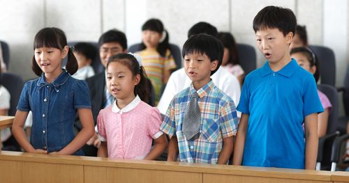 Primary-age children stand while singing.