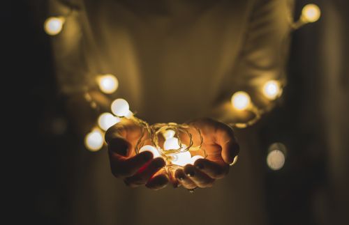 Photo of hands extended holding a string of Christmas lights