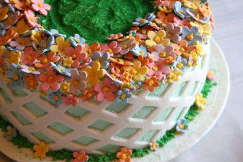 A cake with white and green frosting, topped with edible flower confetti.