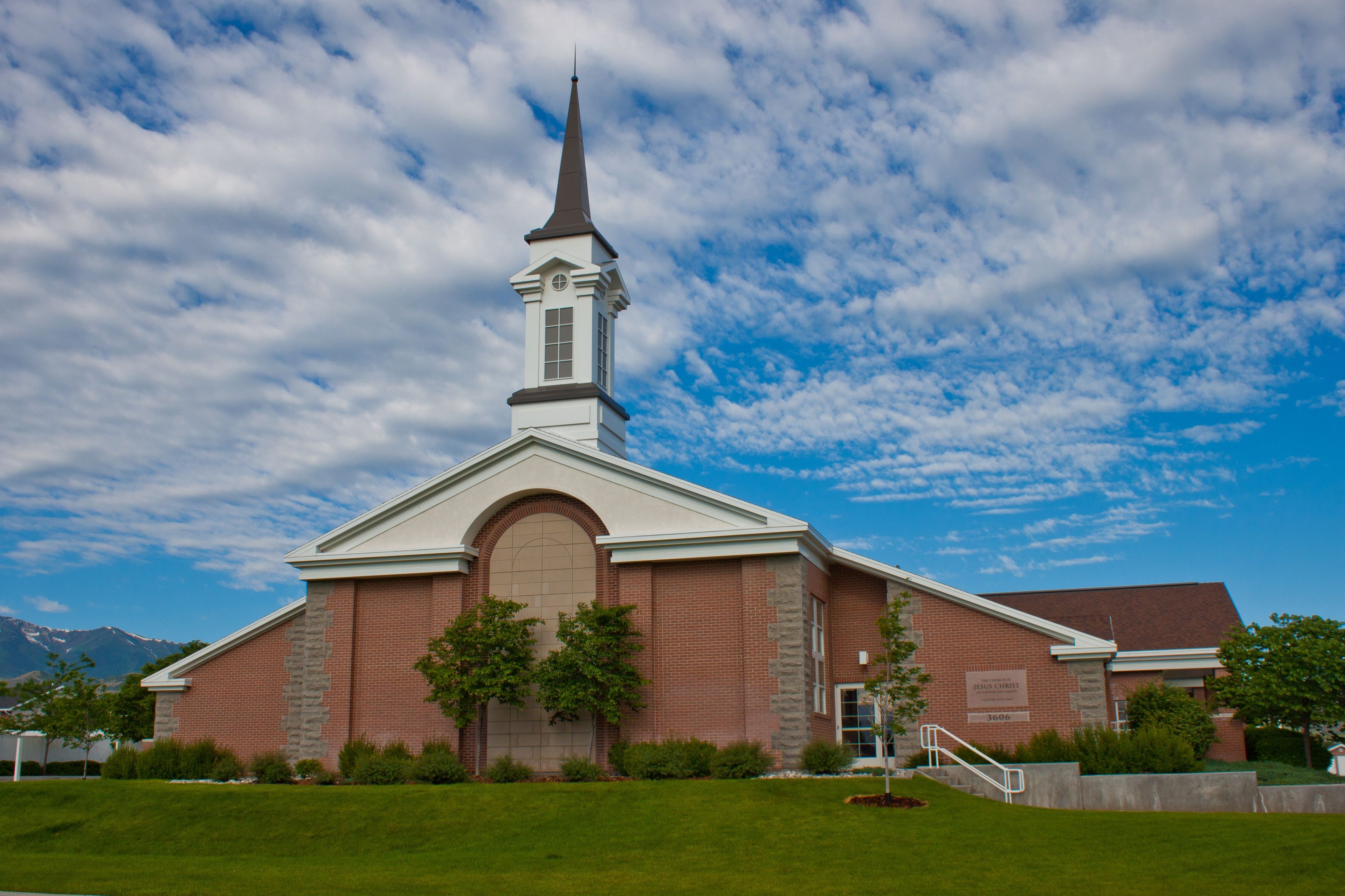 A large red-brick chapel with a blue sky and clouds above.