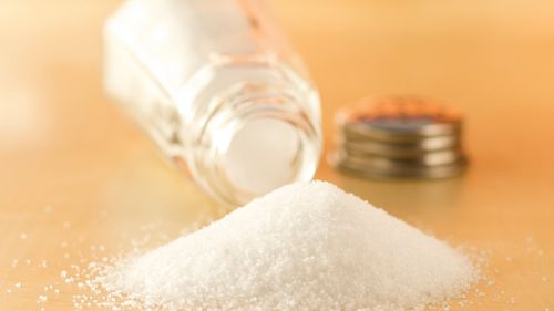 pile of salt next to an open and tipped over saltshaker