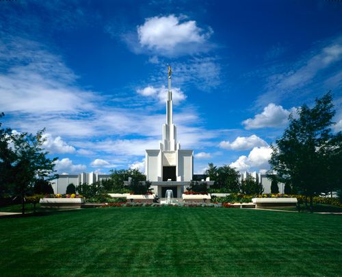 A freshly mowed lawn and a fountain in front of the Denver Colorado Temple on a sunny day with a few clouds.