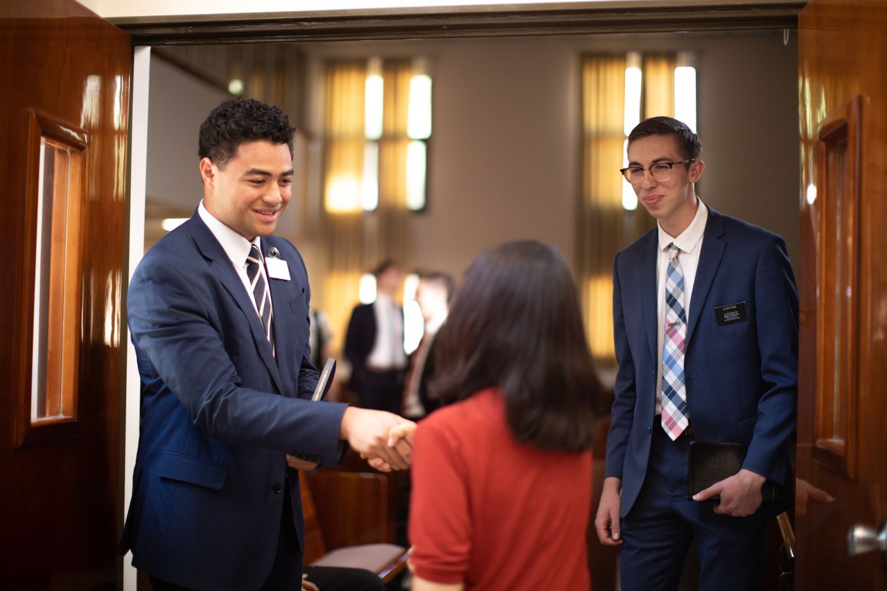 Los misioneros saludan a una mujer a las puertas de la capilla