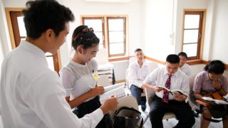 Youth sitting and listening to teacher at church meeting in Thailand