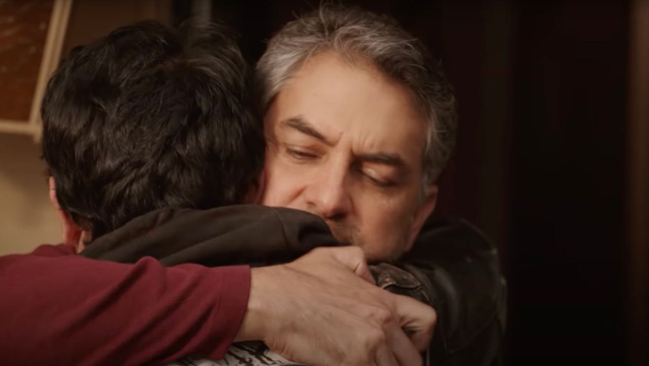 A man hugs his son after having been away for a long time