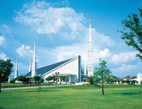 A large lawn in front of the Dallas Texas Temple, with a blue sky and large white clouds overhead.