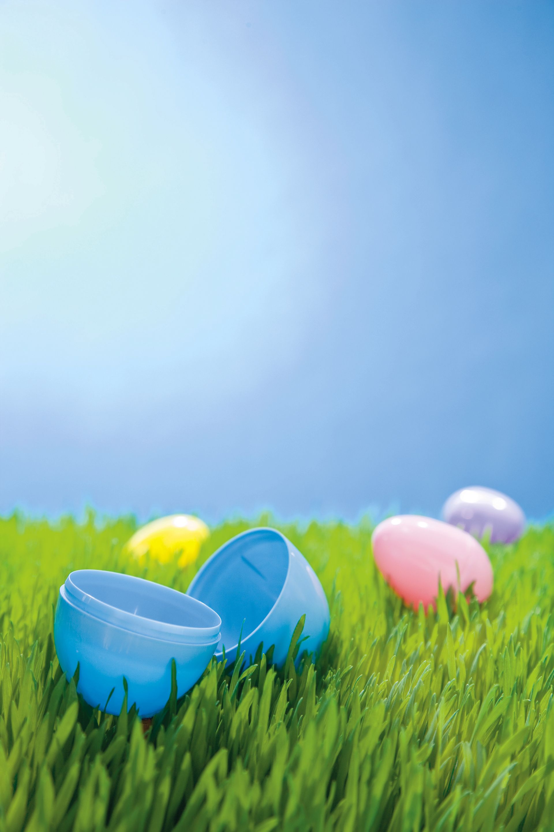 Several plastic Easter eggs lying in green grass.