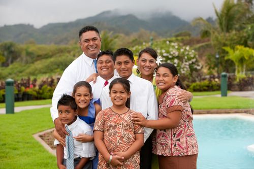 A family of eight huddling together on a stormy day in Hawaii to smile for an informal family photograph.