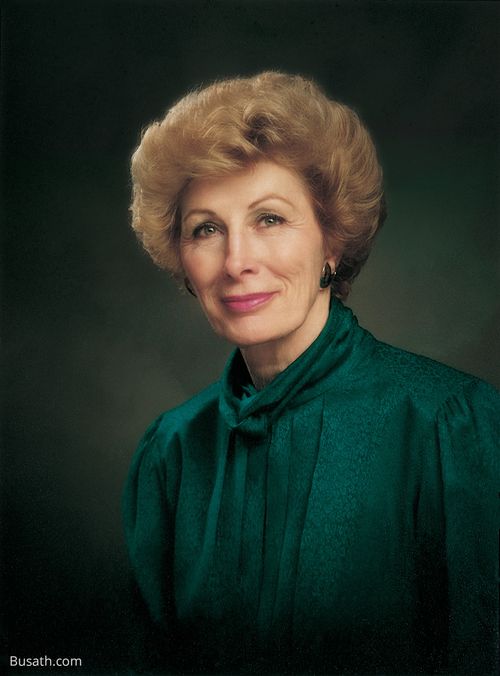A photograph of Elaine Low Jack against a gray background, wearing a dark green blouse.