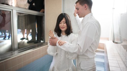a man baptizing a woman in a baptismal font