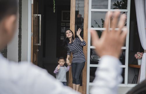 mother and child waving goodbye to father