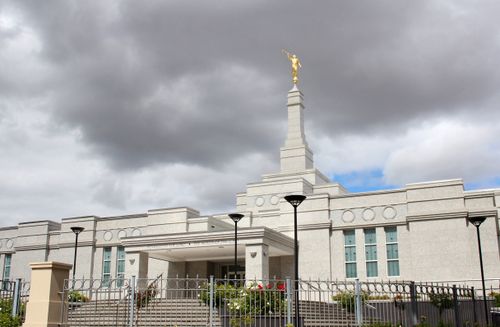 The Perth Australia Temple behind a fence, with gray clouds overhead.