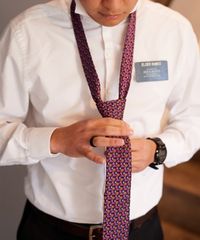A missionary models appropriate dress and attire. He is putting on an approved tie.
