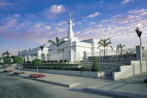 A view of the Guadalajara Mexico Temple from the parking lot, with small white and pink clouds overhead.