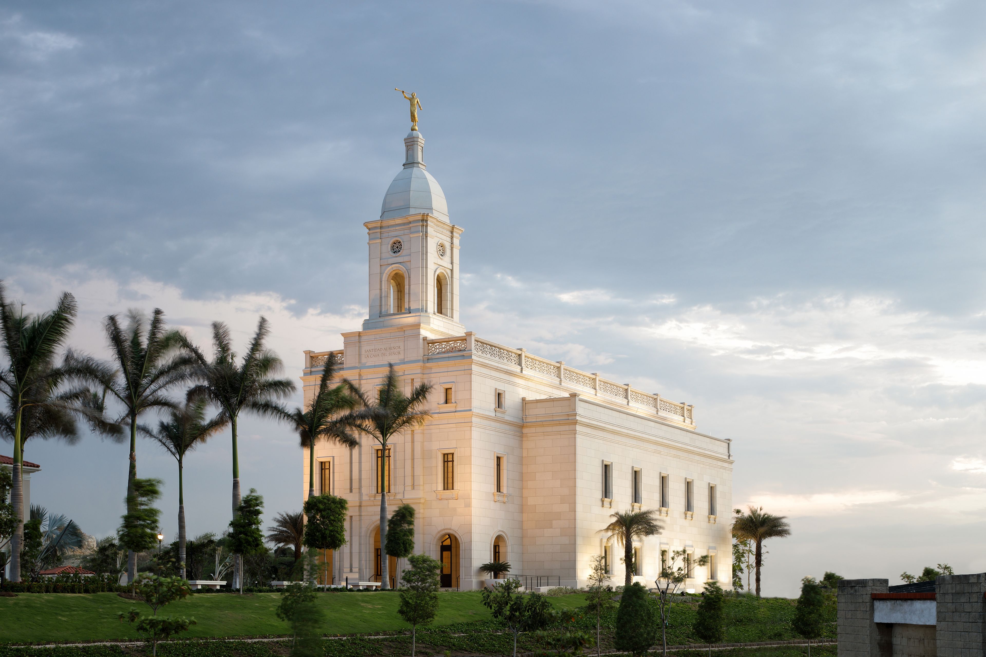 An evening picture of the Barranquilla Colombia Temple surrounded by palm trees.