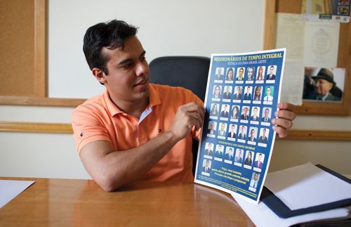 A man holding up chart of missionaries.