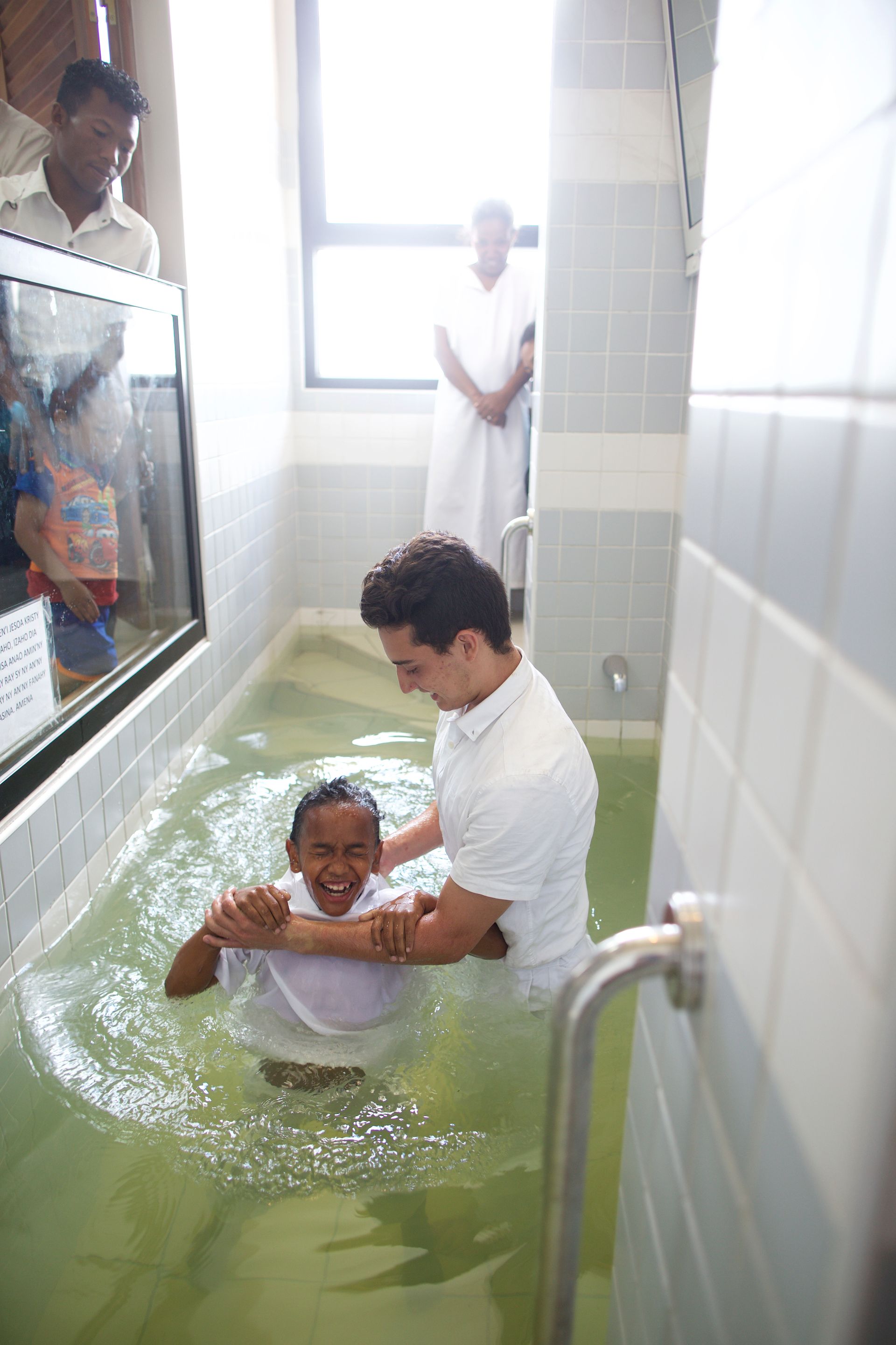 A young boy being baptized in a baptismal font in Madagascar.