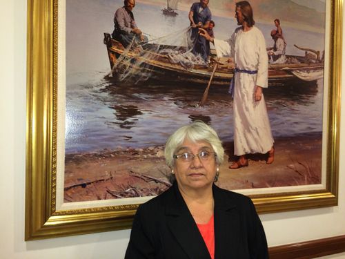 una mujer de pie frente a una pintura de Jesucristo
