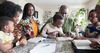 Eine Familie in Afrika sitzt an einem Tisch und liest gemeinsam in den heiligen Schriften