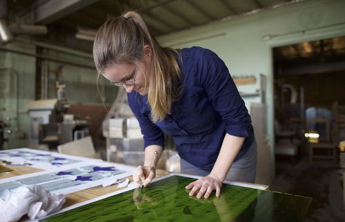 woman cutting stained glass pieces