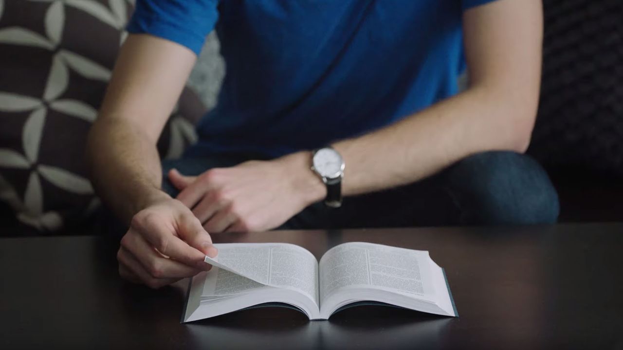 A man reads the Book of Mormon open on a table
