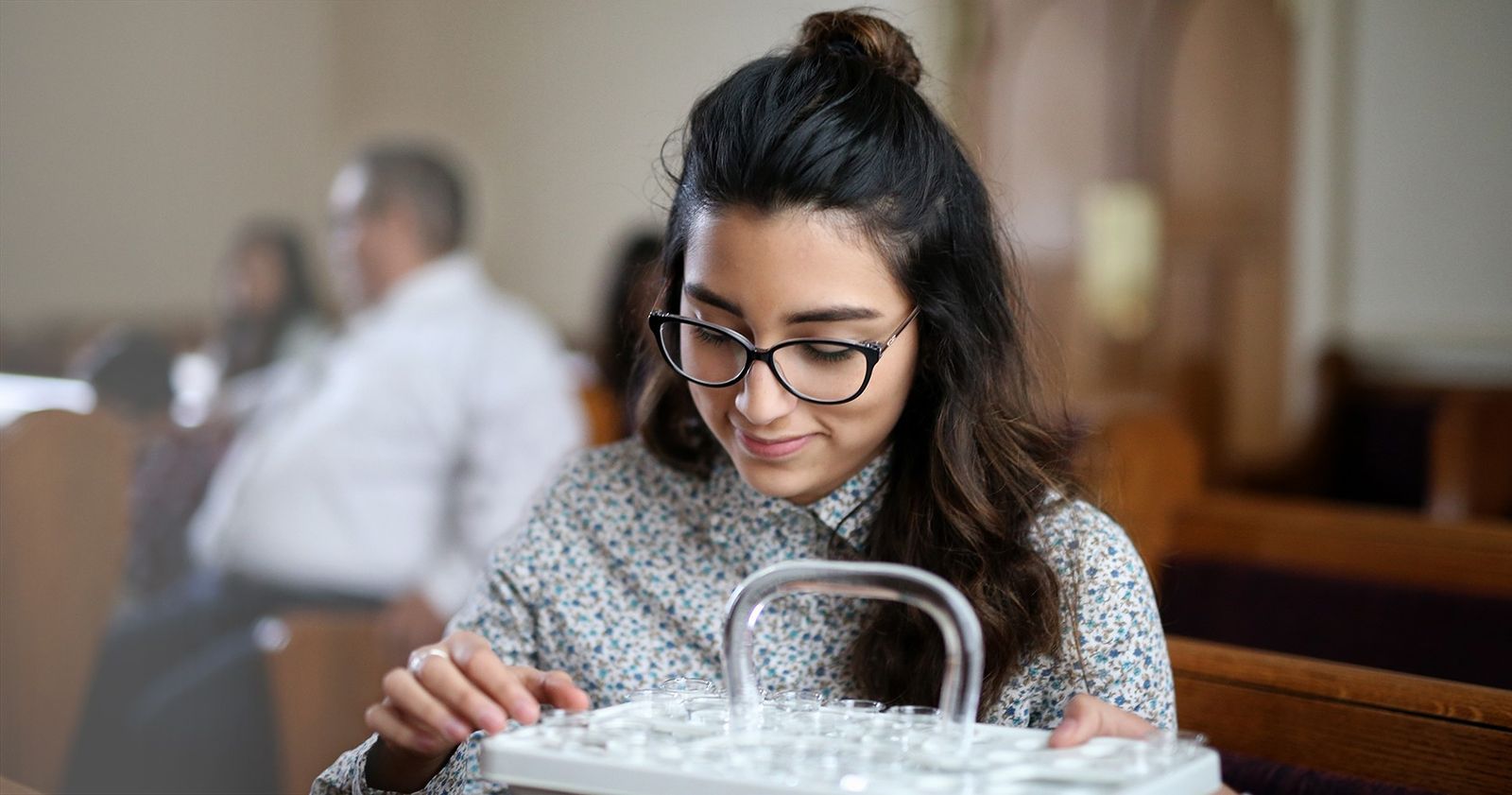A young woman taking the water from a sacrament tray.