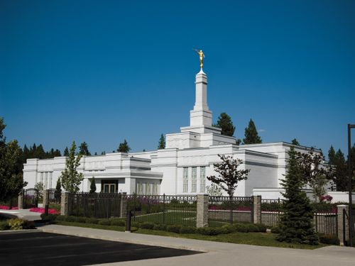 The front of the Spokane Washington Temple, including a view of the entrance, the fence, and trees on the grounds.