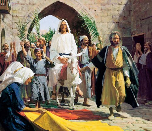 Christ in a white robe, riding a white donkey through a stone archway while a crowd waves palm fronds and lays red and yellow cloths in His path.