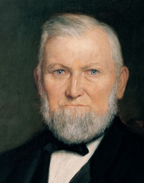 A painted portrait by H. E. Peterson of Wilford Woodruff with a short white beard, wearing a black suit.
