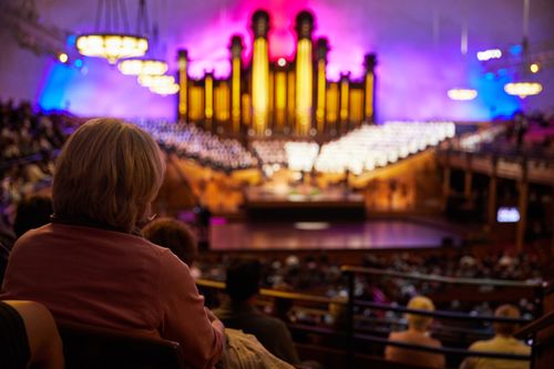 Audiences in the Salt Lake Tabernacle. Audiences sit on the pews. You can see the organ and a choir facing them.