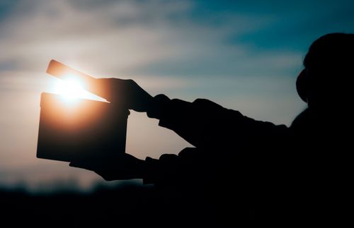 the silhouette of hands holding a clapperboard