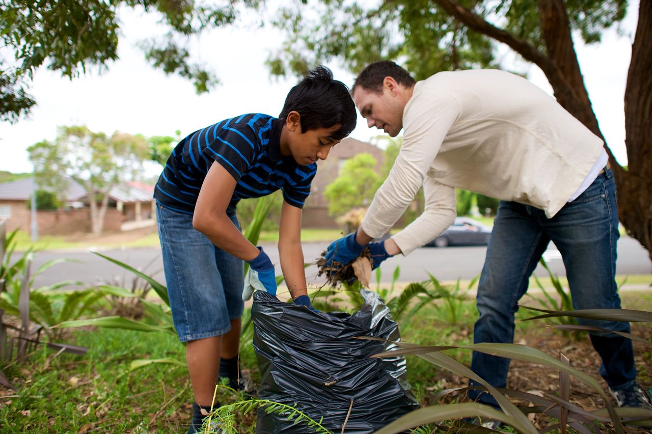 Pai e filho trabalham no jardim como um serviço ao próximo