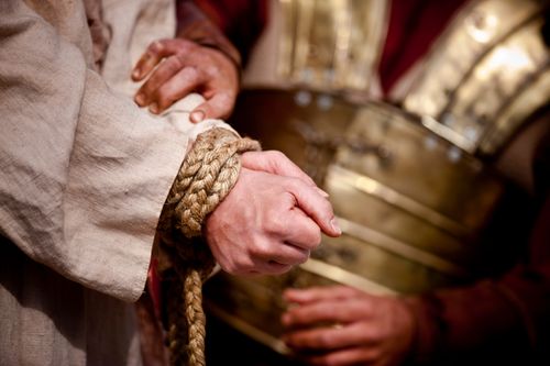 Um soldado romano amarra as mãos de Cristo.