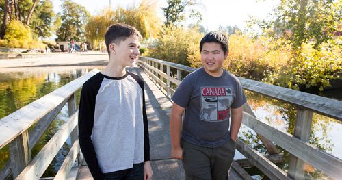 Two youth walk across a bridge