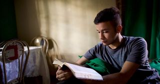 Ein Jugendlicher liest in den heiligen Schriften