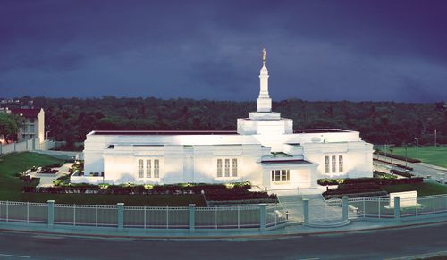 A view of the Veracruz Mexico Temple lit up at night, with the grounds surrounded by a fence.