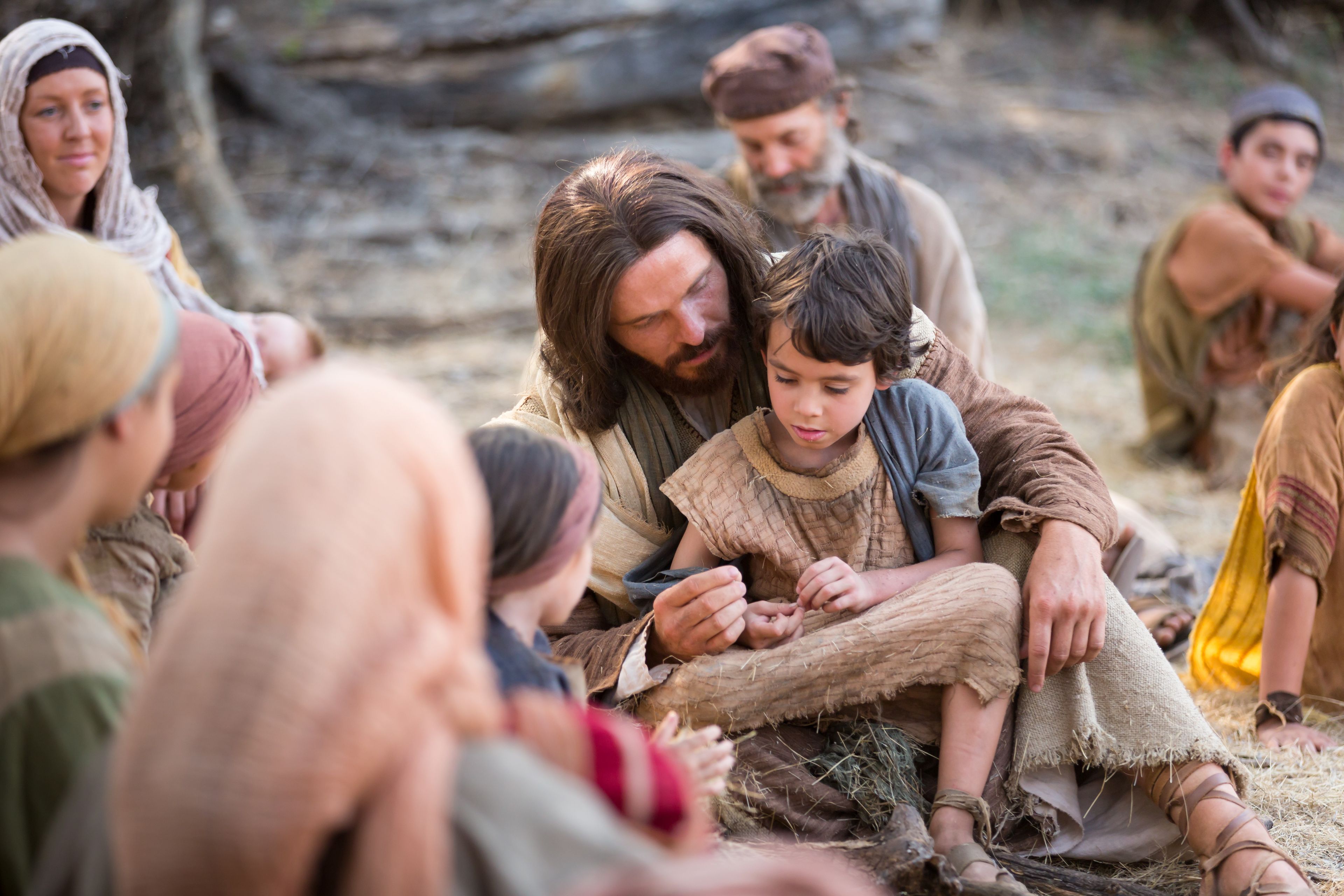Jesus sits with a young child after telling His Apostles, “Suffer little children to come unto me.”
