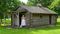 a smiling woman stands out on the porch of a log cabin while holding a broom