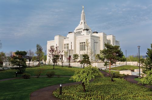 An angled view of the Sapporo Japan Temple with green grass and trees.