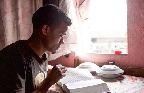 Ein junger Mann liest am offenen Fenster in den Schriften