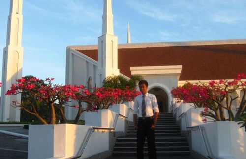 a young adult standing and smiling in front of the temple