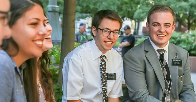 Several young service missionaries meeting together outside.<br>